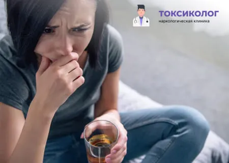 Молодая женщина в отчаянии со стаканом алкоголя. Начните лечение зависимостей сегодня.